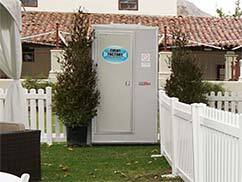 Deluxe portable toilet near Sunnyside, Fresno CA in front of white picket vinyl fencing.
