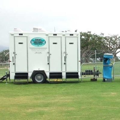 View of Bowles restroom trailer rental next to a blue hand wash station.