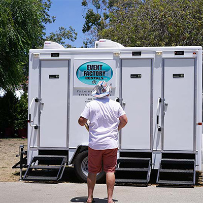 Man standing in front of our Luxury Restroom Trailer, among the Armona music festival and concert event rentals we supply.