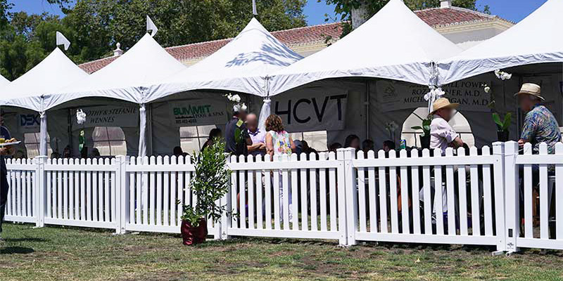 Westlake Village white vinyl picket portable fence panels in front of some covered seating at an outdoor event.
